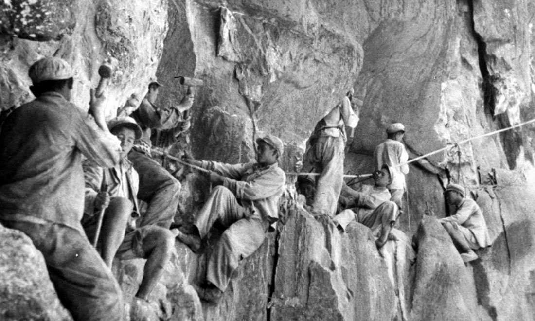 1954年，修筑康藏公路的解放軍戰(zhàn)士們在怒江兩岸的懸崖陡壁上辟山筑路。新華社稿 李萬春、張加里攝